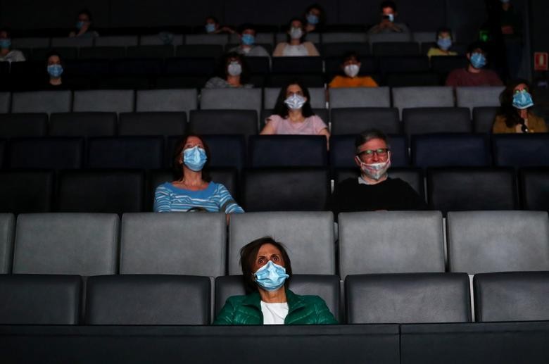 People wearing protective face masks sit keeping social distance before watching a movie at Sala Berlanga cinema, as it reopens during phase two in Madrid, Spain, June 11. REUTERS/Sergio Perez